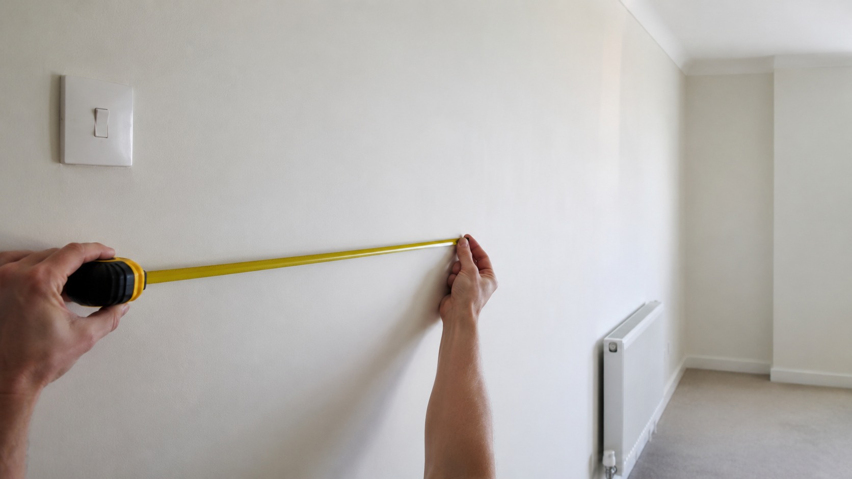 Tape measure held along a clear run of function room wall before a backdrop install