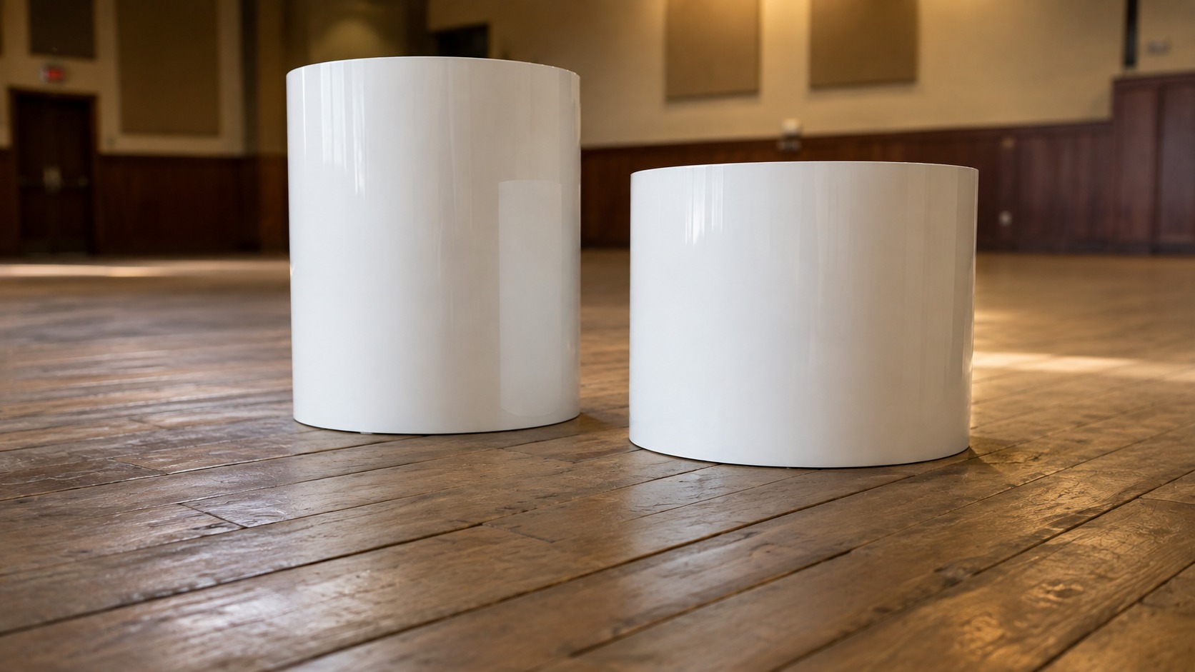 White display plinths standing on an older timber hall floor seen from a low angle