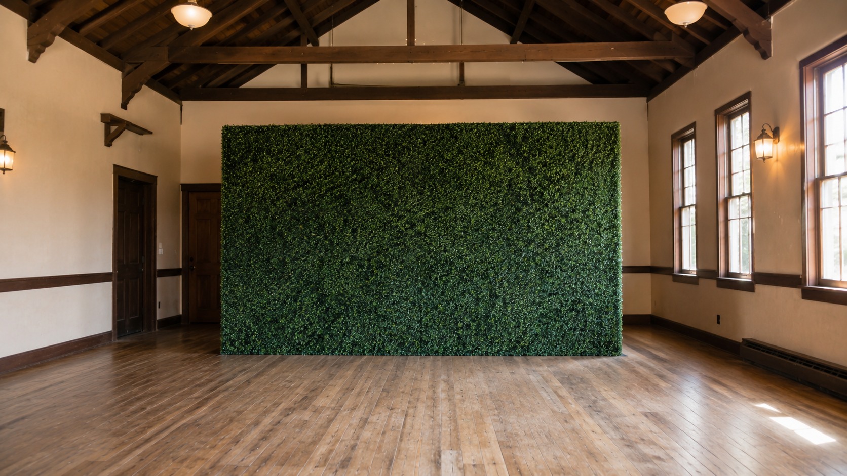 Green boxwood wall set up in an older community hall with exposed roof beams