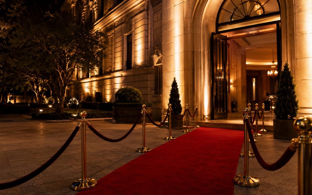 Red carpet entrance with gold rope barriers leading to venue doors at an evening event