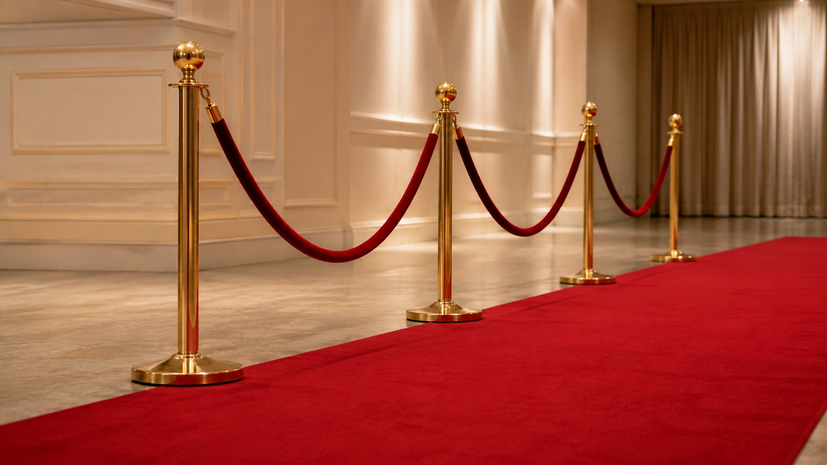 Gold rope barrier posts spaced along a red carpet showing the rope between each pair