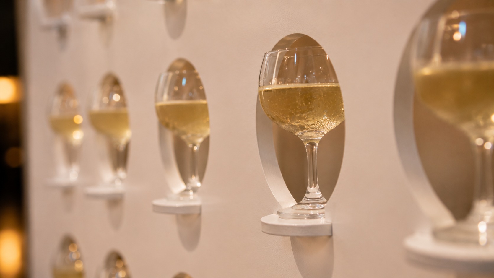 Close view of filled glasses seated in the cut outs of a champagne wall display